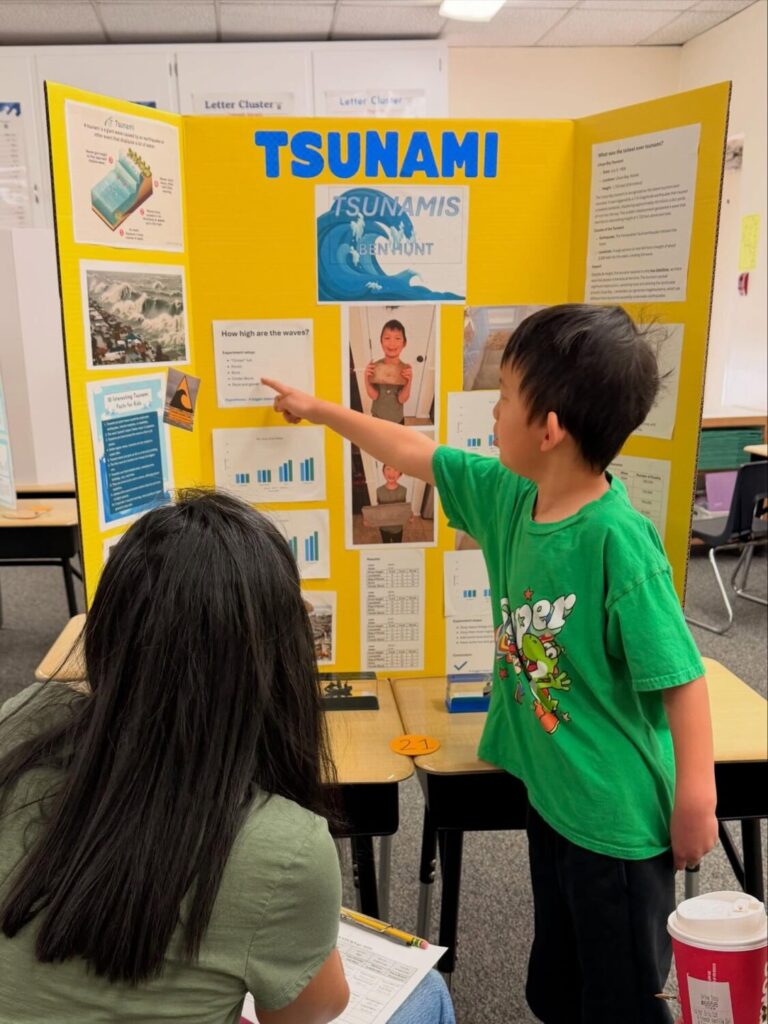 Sunset Mesa Student points to his Tsunami STEM project poster.